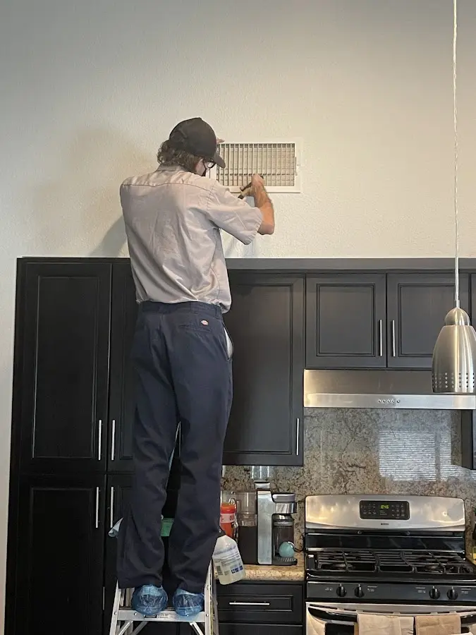 Technician inspecting an air vent during HVAC service in Greeley